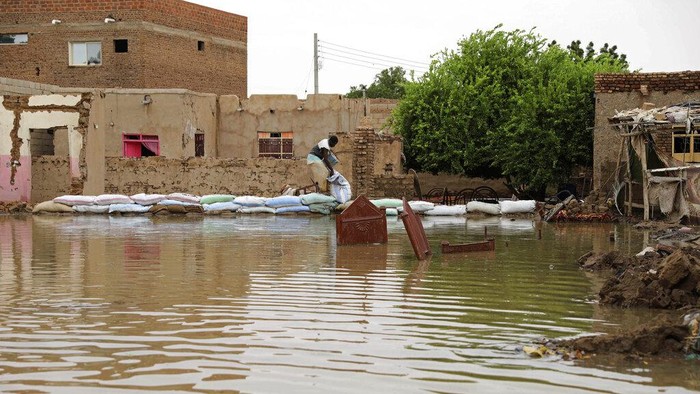 Banjir Sudan People walk on sandbags to reach their homes in the town of Shaqilab, about 15 miles (25 km) southwest of the capital, Khartoum, Sudan, Monday, Aug. 31, 2020. (AP Photo/Marwan Ali)