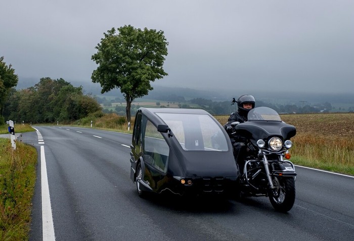 Joerg Grossmann drives his motorcycle combination with a Harley E Glide fitted with a sidecar on a road near Anspach, Germany, on Monday, Aug. 31, 2020. The 56 year old Grossmann who calls himself a chauffeur for the deceased, developed his motorbike hearse for die-hard bikers who want a last ride to their final resting place. in Frankfurt, (AP Photo/Michael Probst)