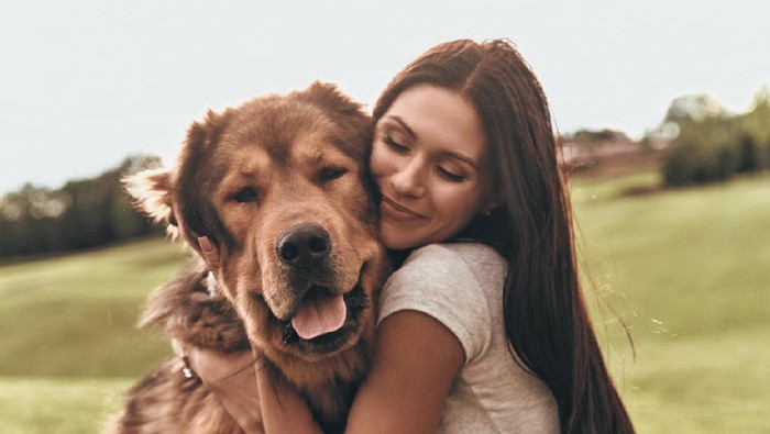 Woman cuddles, plays with her dog at home because of the corona virus pandemic covid-19