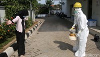 Warga disemprot disinfektan sebelum masuk gedung puskesmas.