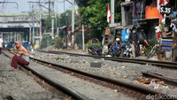 Seorang warga berjemur di pinggir rel kereta api.
