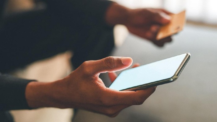 Cropped shot of an unrecognizable man using a credit card and a smartphone to shop online at home