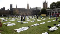 Di alun-alun Parlemen Inggris, para demonstran berbaring di bawah kain putih. AP Photo/Alastair Grant  
