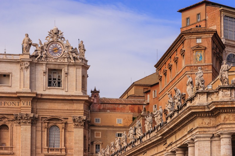 Vatican City, Vatican City State - October 11, 2007: External view of the Sistine Chapel at the Vatican City, seen at the centre of the photo. It is towards this roof that the faithful gathered in Saint Peter's Square look to, for the first signs of a newly elected pope by the Conclave of the College of Cardinals: black smoke denotes that the ballot was inconclusive, white smoke indicates they have a new Pope. The Sistine Chapel is the Pope's private chapel. To the left is a section of St. Peter's Basilica. To the right is a section of the Vatican Museum and Palace. Photo shot in the afternoon sunlight from St. Peter's Square; horizontal format.