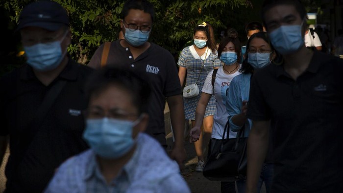 People wearing face masks to protect against the coronavirus walk along a street in the central business district in Beijing, Wednesday, Sept. 2, 2020. Even as China has largely controlled the outbreak, the coronavirus is still surging across parts of the world. (AP Photo/Mark Schiefelbein)