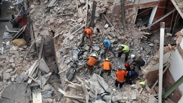 Lebanese and Chilean rescuers search in the rubble of a collapsed building after getting signals there may be a survivor, early Friday, Sept. 4, 2020, in Beirut, Lebanon. A pulsing signal was detected Thursday from under the rubble of a Beirut building that collapsed during the horrific port explosion in the Lebanese capital last month, raising hopes there may be a survivor still buried there. (AP Photo/Hussein Malla)