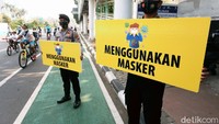 Petugas kepolisian melakukan sosialisasi protokol kesehatan dengan membawa poster di jalan Sudirman-MH Thamrin, Jakarta, Minggu (06/09/2020).