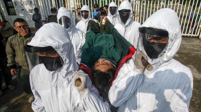 Petugas Satpol PP Kabupaten Bogor menggunakan pakaian hazmat membawa seorang pelanggar PSBB pra Adaptasi Kebiasaan Baru (AKB) dengan tandu menuju pemakaman di kawasan Stadion Pakansari, Kabupaten Bogor, Jawa Barat, Minggu (6/9/2020). Pemerintah Kabupaten Bogor menerapkan sanksi denda sebesar Rp100 ribu serta sanksi sosial yakni kewajiban membersihkan area makam, push up dan  tahapan prosesi pemakaman COVID-19, hal tersebut untuk memberikan efek jera bagi warga yang tidak menggunakan masker di tempat umum. ANTARA FOTO/Yulius Satria Wijaya/foc.
