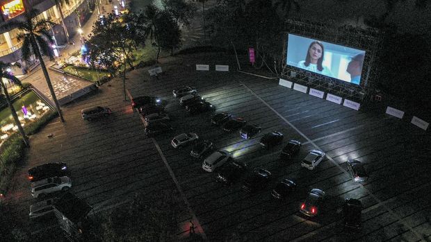 Pengunjung berada di dalam mobil saat menyaksikan film di 