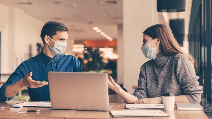 Ilustrasi pakai masker di tempat kerja close up. business colleagues in protective masks sitting at the office Desk.