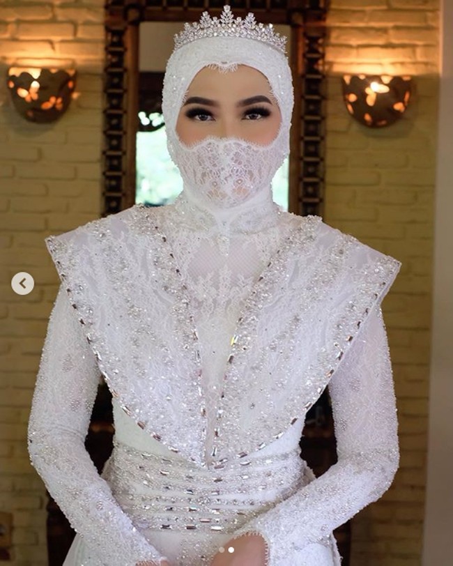 Inge Amalia Nasution dan pria idamannya, Adit, menikah pada akhir pekan kemarin di Plataran Cilandak, Jakarta. Pada hari bahagianya itu, Inge tampil serba putih. Mulai dari gaun pengantin, hijab hingga masker yang dipakainya berwarna putih. Foto: Dok. Instagram @bennusorumba
