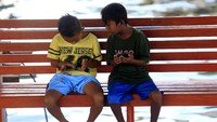 Dua bocah bermain gawai dengan memanfaatkan fasilitas wifi gratis.