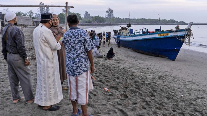 An ethnic Rohingya woman is assisted to walk by others after the boat carrying them landed in Lhokseumawe, Aceh province, Indonesia, early Monday, Sept. 7, 2020. Almost 300 Rohingya Muslims were found on a beach in Indonesias Aceh province Monday and were evacuated by military, police and Red Cross volunteers, authorities said. (AP Photo/Zik Maulana)