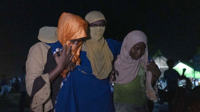 An ethnic Rohingya woman is assisted to walk by others after the boat carrying them landed in Lhokseumawe, Aceh province, Indonesia, early Monday, Sept. 7, 2020. Almost 300 Rohingya Muslims were found on a beach in Indonesias Aceh province Monday and were evacuated by military, police and Red Cross volunteers, authorities said. (AP Photo/Zik Maulana)