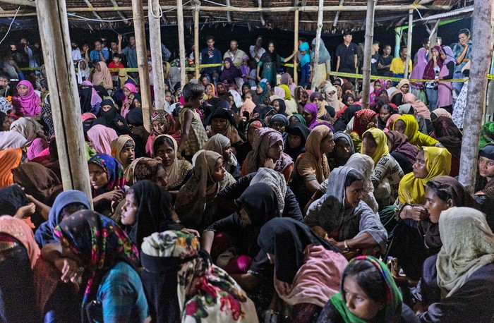 An ethnic Rohingya woman is assisted to walk by others after the boat carrying them landed in Lhokseumawe, Aceh province, Indonesia, early Monday, Sept. 7, 2020. Almost 300 Rohingya Muslims were found on a beach in Indonesias Aceh province Monday and were evacuated by military, police and Red Cross volunteers, authorities said. (AP Photo/Zik Maulana)