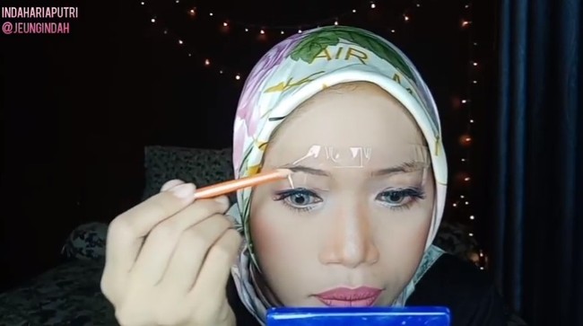 Agar lebih mudah membentuk alis, kamu juga bisa menggunakan isolasi sebagai alat bantumu loh.. Dijamin alis yang kamu buat tidak akan keluar jalur. Sangat kreatif bukan? Foto: YouTube/Indah Putri Official