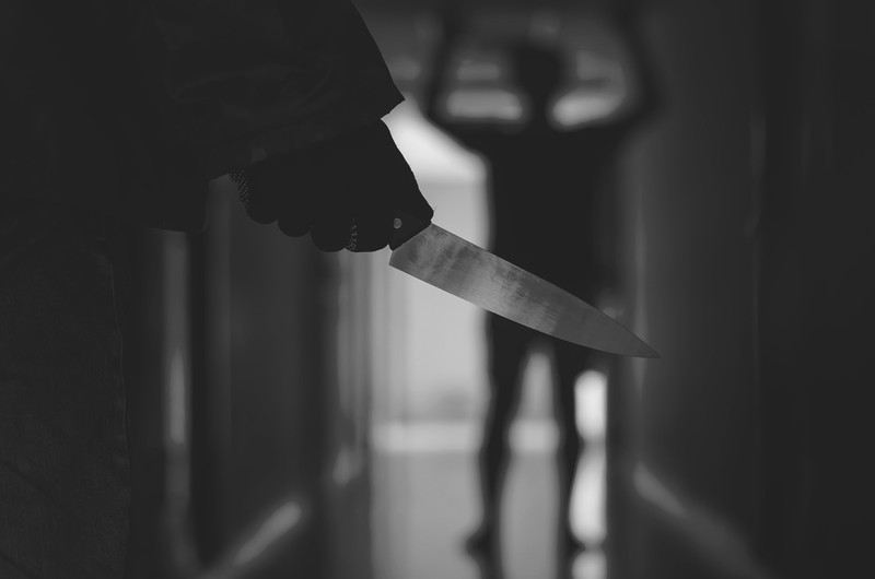 Close up of Hand with knife following young terrified man ,Bandit is holding a knife in hand. Threat Concept