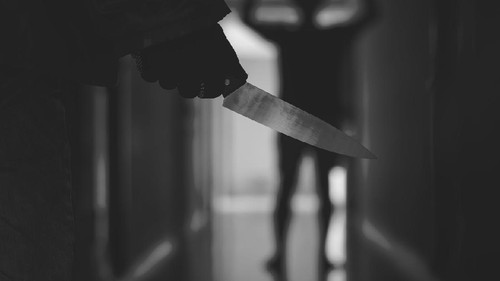 Close up of Hand with knife following young terrified man ,Bandit is holding a knife in hand. Threat Concept