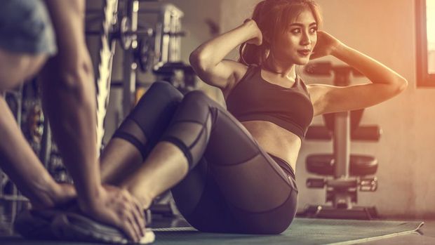 Fitness woman doing sit-ups exercises.Female doing abs workout with personal trainer