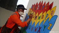 Seorang petugas menyelesaikan lukisan di tiang tol Becakayu.