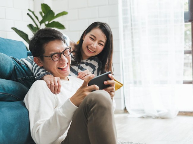 Lifestyle Asian couple man and woman playing game on mobile phone together at home, Asian couple family lifestyle concept