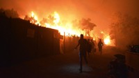 Pada malam hari, para migran di kamp pengungsi Moria melarikan diri dari kebakaran yang terjadi di beberapa titik dan memusnahkan sebagian besar kamp dan perkebunan zaitun di lereng bukit.  
