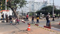 Pejalan kaki mengolong di palang perlintasan kereta api yang ditutup.