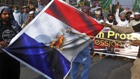 Massa tampak membawa poster yang merepresentasikan bendera negara Prancis saat melakukan aksi unjuk rasa di kawasan Lahore, Pakistan. AP Photo/K.M. Chaudary.