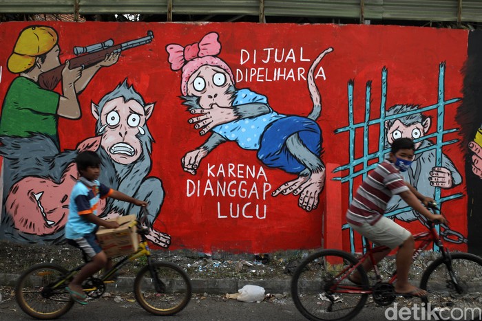 Warga melintas di depan Lukisan mural bertema peduli satwa monyet terpampang di dinding Pasar Satwa dan Tanaman Hias Yogyakarta, Jumat (11/9/2020).
