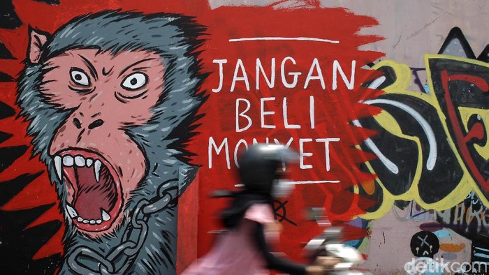 Mural Anti Perdagangan Hewan Warga melintas di depan Lukisan mural bertema peduli satwa monyet terpampang di dinding Pasar Satwa dan Tanaman Hias Yogyakarta, Jumat (11/9/2020).