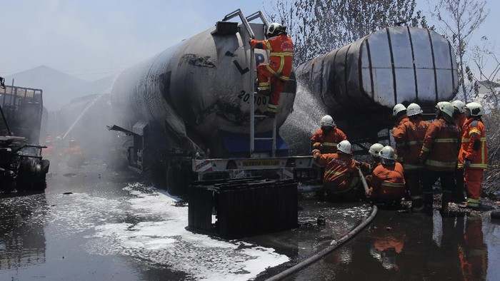 Petugas Dinas Pemadam Kebakaran Kota Surabaya melakukan pembasahan truk tangki yang terbakar di kawasan Dumar Industri, Surabaya, Jawa Timur, Sabtu (12/9/2020). Sekitar 18 kendaraan pemadam kebakaran dikerahkan untuk memadamkan kebakaran diduga berawal dari kebakaran alang-alang yang merembet serta membakar lima truk tangki tersebut. ANTARA FOTO/Didik Suhartono/hp.