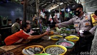 Petugas Polsek Sunda Kelapa membagikan masker kepada warga di kawasan Pasar Muara Angke, Jakarta Utara, Senin (14/9/2020).