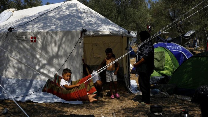 A man pray inside a make shift tent near the burned Moria camp on island of Lesbos, Greece, Sunday Sept. 13, 2020. Greek authorities have been scrambling to find a way to house more than 12,000 people left in need of emergency shelter on the island after the fires deliberately set on Tuesday and Wednesday night gutted the Moria refugee camp. (AP Photo/Petros Giannakouris)