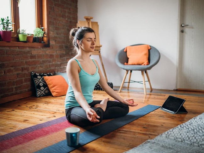 Young woman relaxing herself practicing meditation at her home