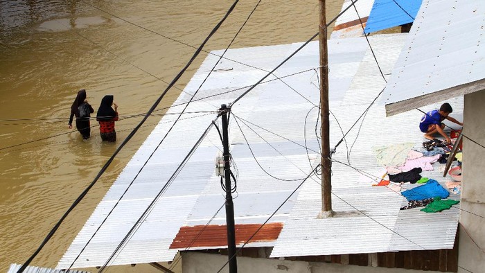 Seorang anak menjemur baju di atap rumahnya yang tergenang banjir di Jalan Ngurah Rai, Putussibau, Kabupaten Kapuas Hulu, Kalimantan Barat, Selasa (15/9/2020). Kota Putussibau masih terendam banjir dan mengalami pemadaman listrik serta jaringan telekomunikasi sejak Minggu (13/9/2020). ANTARA FOTO/Jessica Helena Wuysang/foc.