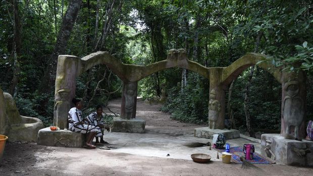 Women sit at the gate of Shrines of the Osun River at the Oshogbo Sacred Grove, the last sacred  forest in southwest Nigeria, on June 3, 2020. - The dense forest Osun-Oshogbo Sacred Grove is believed to host the ethnic Yoruba goddess of fertility, spirit of Osun, other deities associated with water, purity, and artworks, places of worship, in addition to natural herbal pharmacy containing hundreds different species of plants. (Photo by PIUS UTOMI EKPEI / AFP)