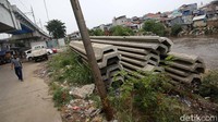Warga melitas di dekat sheet pile beton yang mangkrak dipinggir Kali Ciliwung.