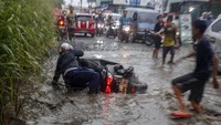 Tampak seorang pengendara motor terjatuh saat melintasi Jalan Raya Bojong Gede-Citayam yang banjir di Bojong Gede, Kabupaten Bogor, Jawa Barat. Salah satu akses jalan menuju kawasan Pemerintahan Kabupaten Bogor dan stasiun kereta tersebut rusak dan berlubang sehingga digenangi air sehabis hujan sehingga membahayakan bagi pengendara dan menyebabkan kemacetan.