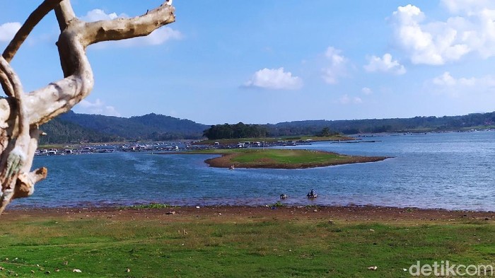 Pulau batu datar muncul ke permukaan Waduk Darma yang surut