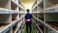 Seorang karyawan sedang beraktivitas di dalam gudang. Dia beraktivitas dengan menerapkan protokol kesehatan seperti memakai masker.