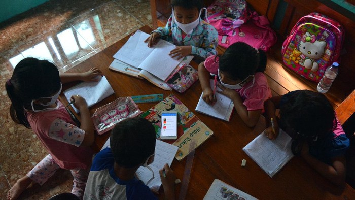 Sejumlah siswa kelas 6 SDN Sumberaji 2 mengerjakan tugas pelajaran sekolah secara daring atau online di kawasan makam Dusun Ngapus, Desa Sumberaji, Kecamatan Kabuh, Kabupaten Jombang, Jawa Timur.