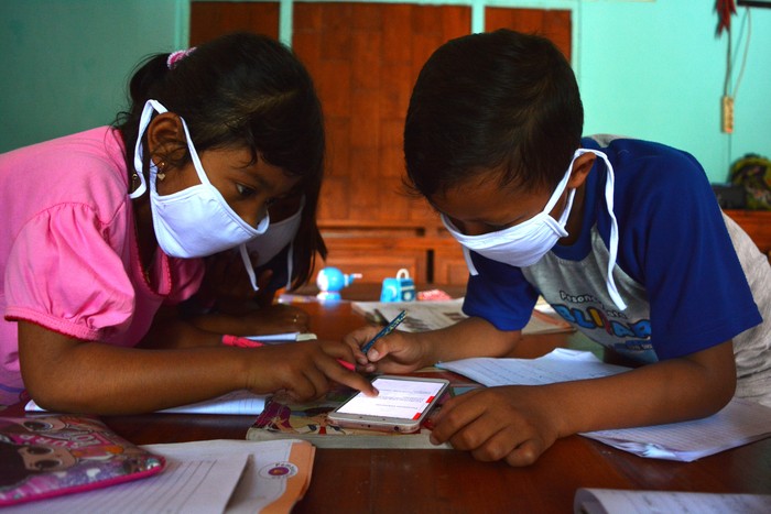 Sejumlah siswa kelas 6 SDN Sumberaji 2 mengerjakan tugas pelajaran sekolah secara daring atau online di kawasan makam Dusun Ngapus, Desa Sumberaji, Kecamatan Kabuh, Kabupaten Jombang, Jawa Timur.