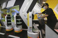 In this Sunday, Sept. 13, 2020, photo, a robot carries a takeout bag with food at No Brand Burger in Seoul, South Korea. From order to pick-up, customers don’t need a single face-to-face interaction. All they need to do is to click the menu they want on a kiosk touchscreen, pay and wait for a serving robot to bring their takeout bag to the pick-up spot. (AP Photo/Ahn Young-joon)
