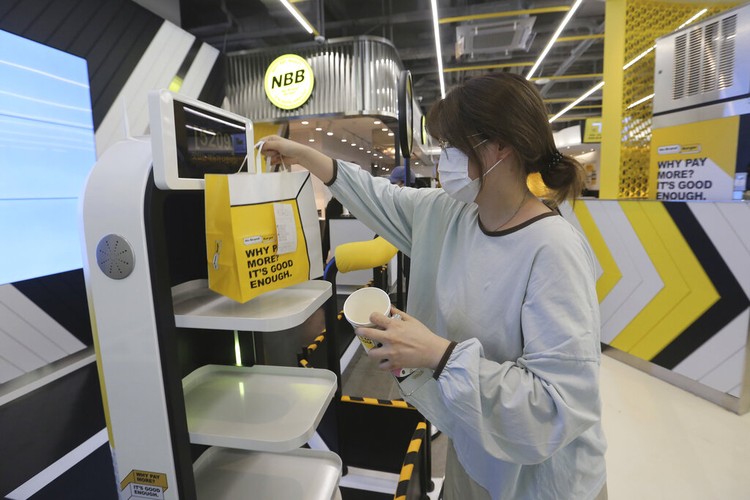 In this Sunday, Sept. 13, 2020, photo, a robot carries a takeout bag with food at No Brand Burger in Seoul, South Korea. From order to pick-up, customers don’t need a single face-to-face interaction. All they need to do is to click the menu they want on a kiosk touchscreen, pay and wait for a serving robot to bring their takeout bag to the pick-up spot. (AP Photo/Ahn Young-joon)