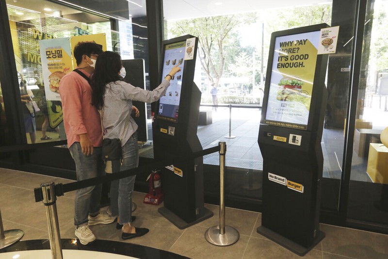 In this Sunday, Sept. 13, 2020, photo, a robot carries a takeout bag with food at No Brand Burger in Seoul, South Korea. From order to pick-up, customers don’t need a single face-to-face interaction. All they need to do is to click the menu they want on a kiosk touchscreen, pay and wait for a serving robot to bring their takeout bag to the pick-up spot. (AP Photo/Ahn Young-joon)