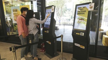 Sepasang kekasih menggunakan kios layar sentuh untuk memesan makanan di No Brand Burger di Seoul, Korea Selatan. Di beberapa restoran Korea Selatan dari pemesanan hingga pengambilan, pelanggan tidak memerlukan satu interaksi tatap muka. AP Photo/Ahn Young-joon   