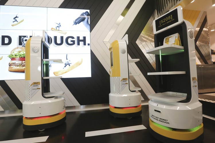 In this Sunday, Sept. 13, 2020, photo, a robot carries a takeout bag with food at No Brand Burger in Seoul, South Korea. From order to pick-up, customers don’t need a single face-to-face interaction. All they need to do is to click the menu they want on a kiosk touchscreen, pay and wait for a serving robot to bring their takeout bag to the pick-up spot. (AP Photo/Ahn Young-joon)