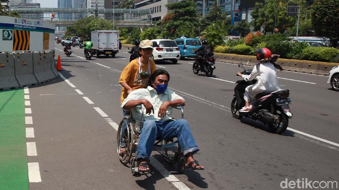 Trotoar di Jalan Thamrin, Jakarta Pusat, digunakan dalam proyek MRT. Hal ini membuat seorang pengguna kursi roda terpaksa melintas di tengah jalan.