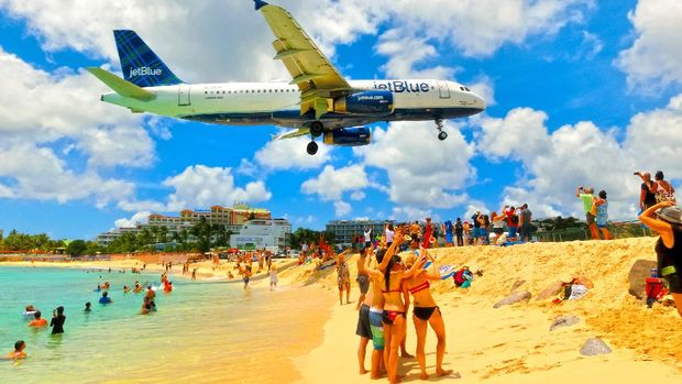 Philipsburg, Sint Maarten, Netherlands - May 14, 2016: The beach at Maho Bay is one of the world's premier planespotting destinations. Airplanes landing at the Princess Juliana Airport fly over beachgoers.