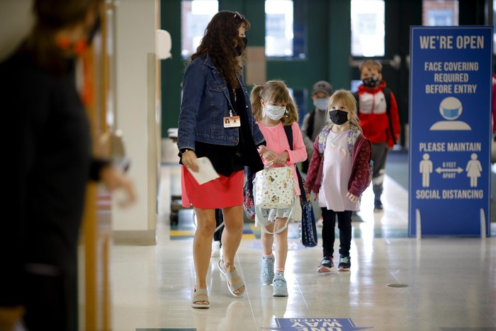Kindergarten students are led into the building on the first day of in-person classes at Lee Elementary School on Wednesday, Sept. 16, 2020  in Lee, Mass. (Stephanie Zollshan/The Berkshire Eagle via AP)